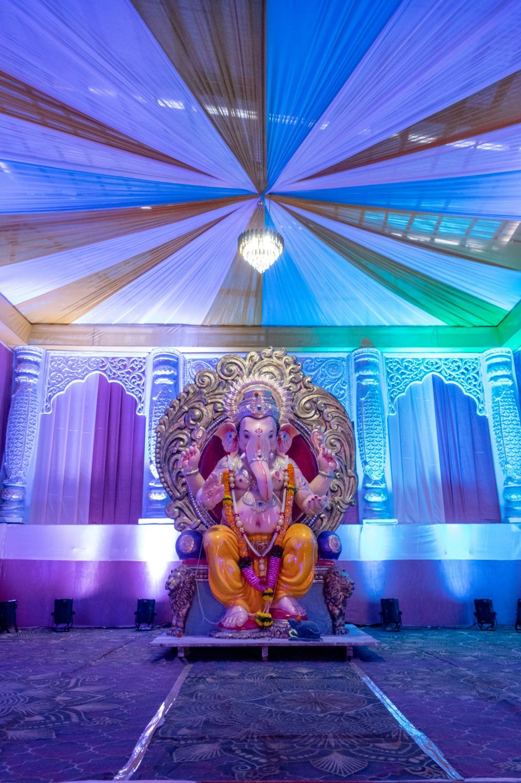 Ornate Ganesh idol on the mandapam stage beneath a draped, lit canopy