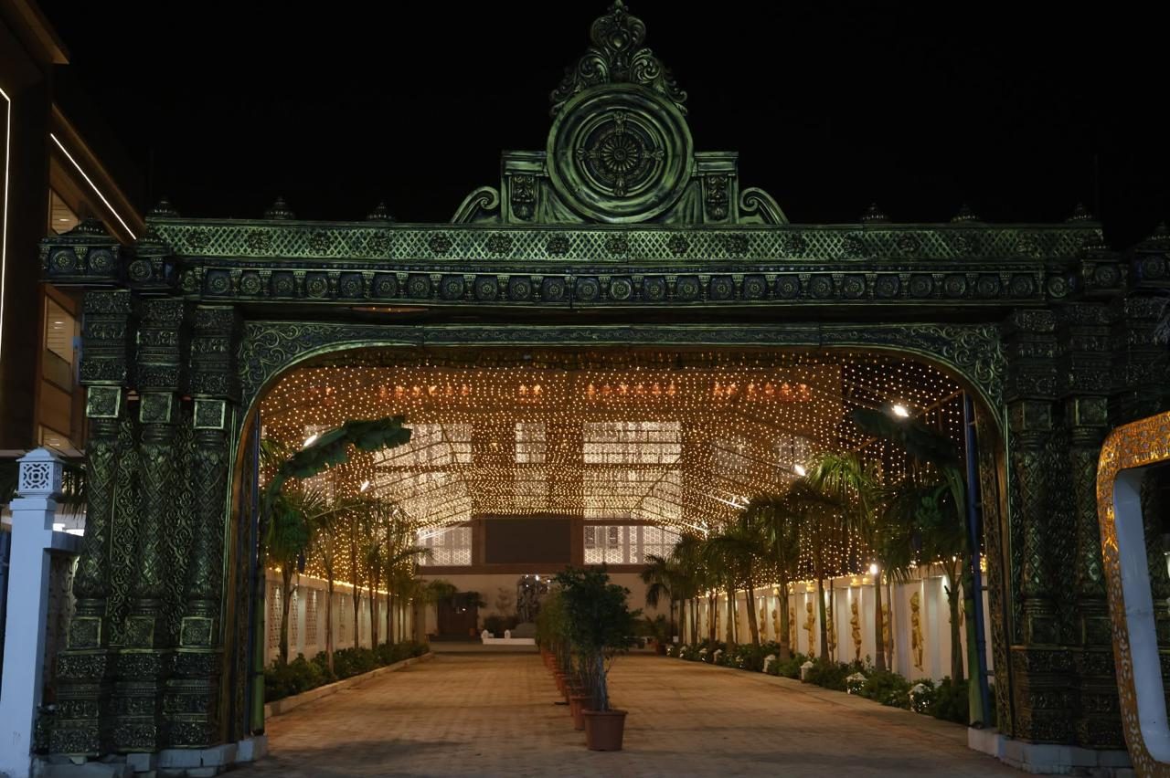 Ornamental entrance gateway lit at night with a lantern-lit walkway beyond