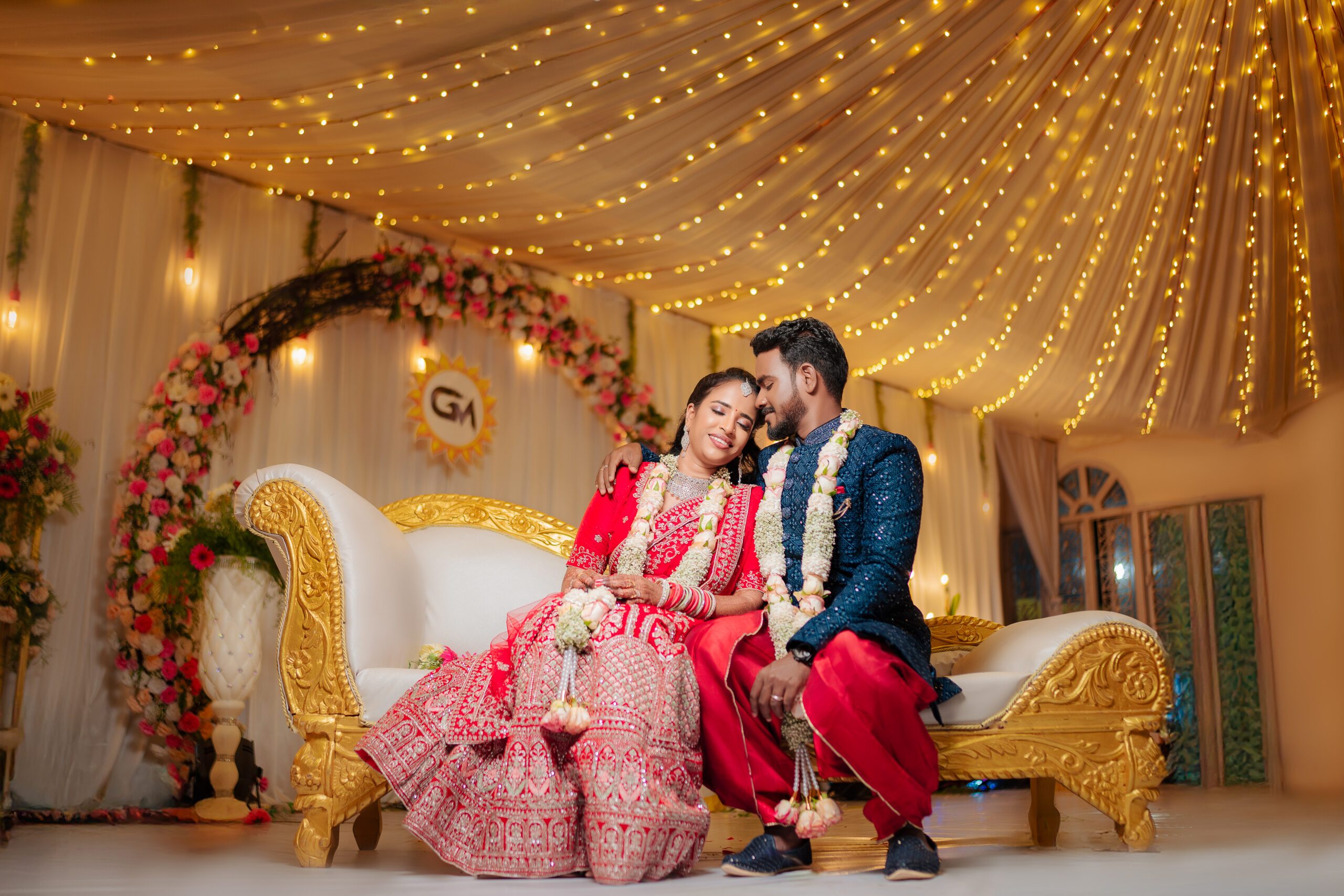 Couple seated together at an engagement ceremony under fairy-lit drapes