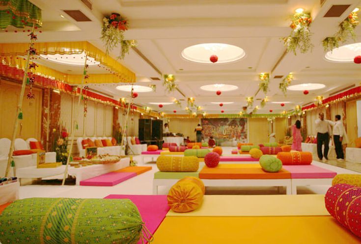 Festively decorated hall with floor seating set up for a religious or traditional function